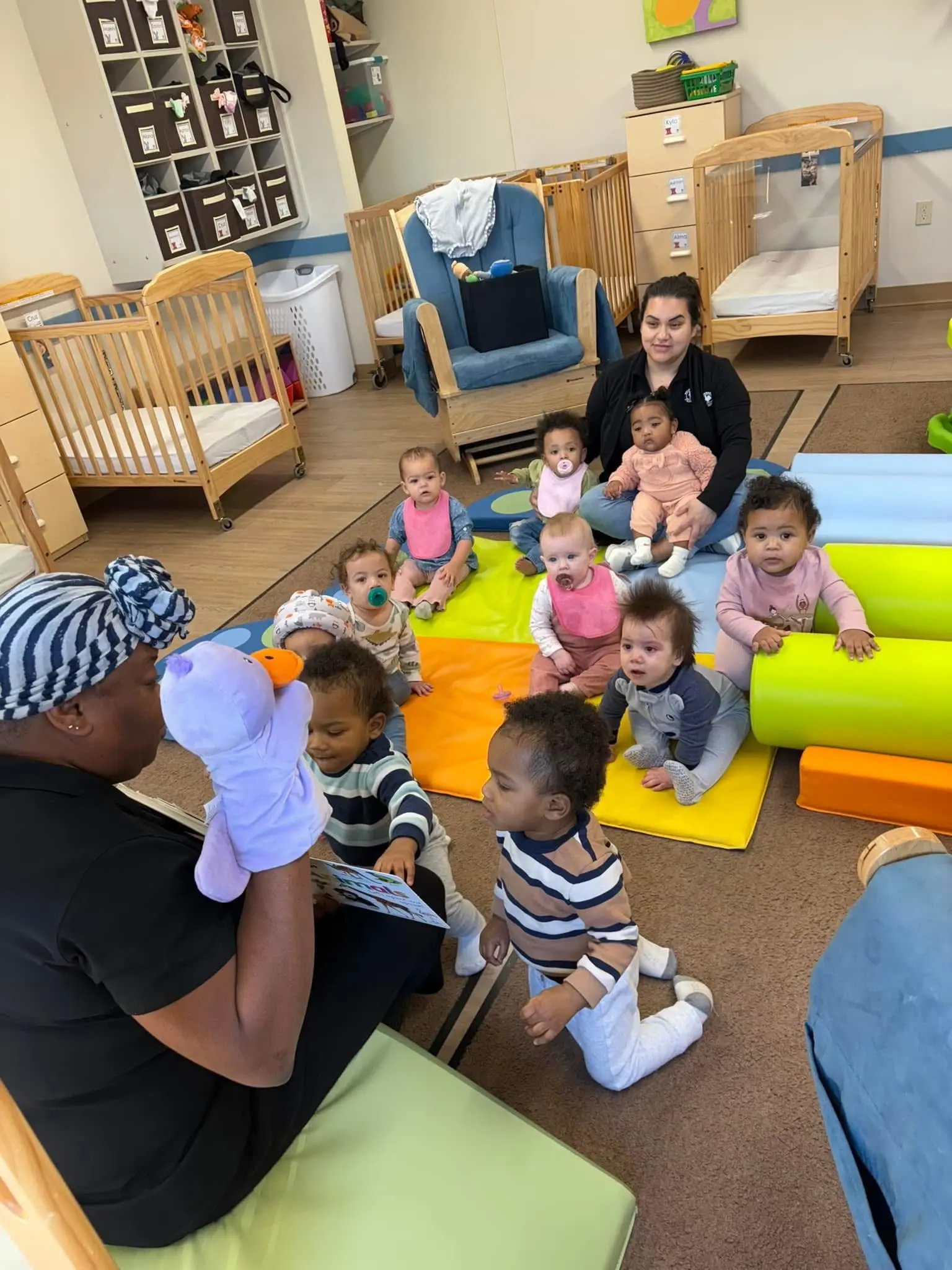 Babies look at book with teachers, daycare near me