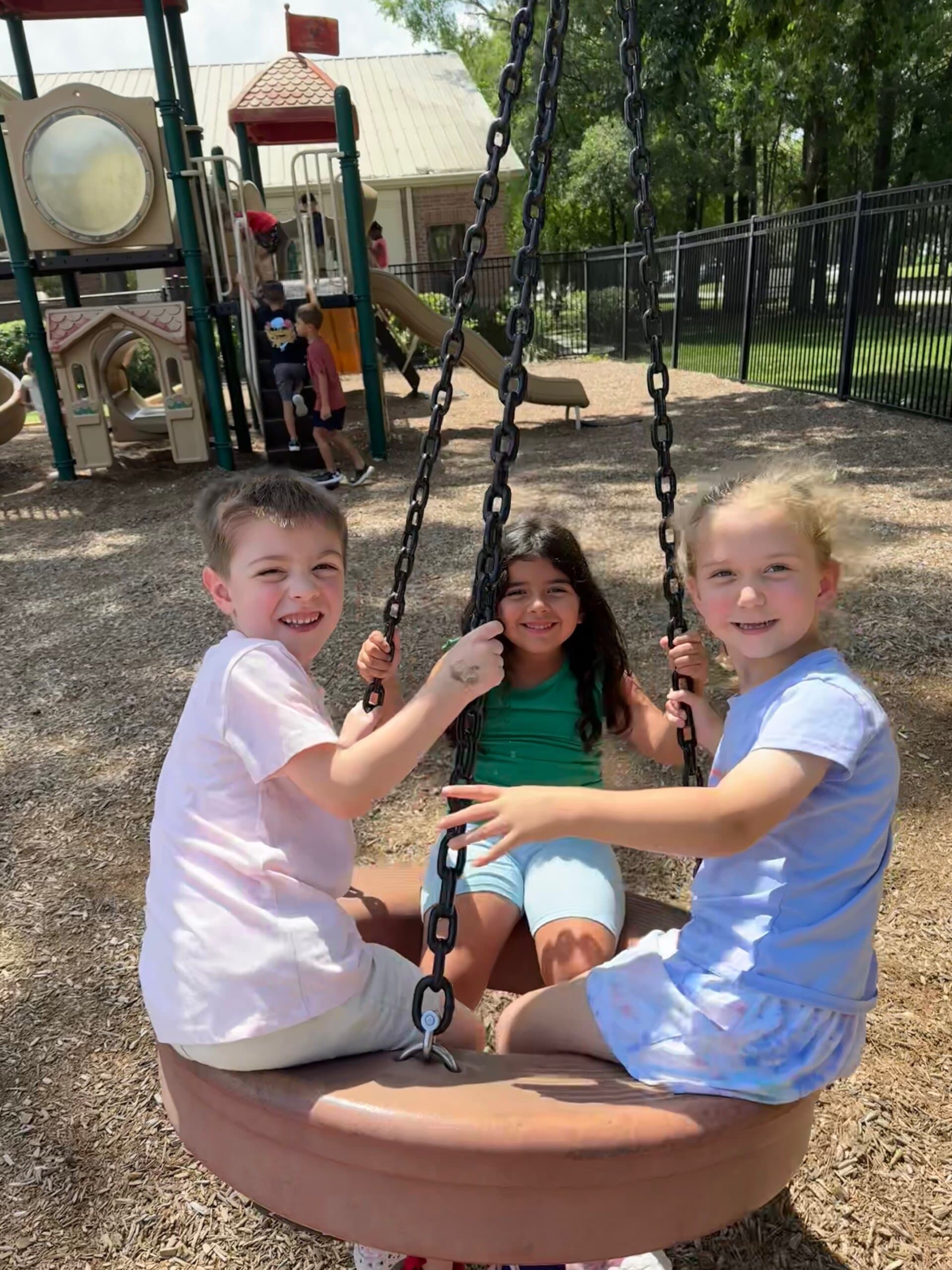 Students play on a tire swing and smile