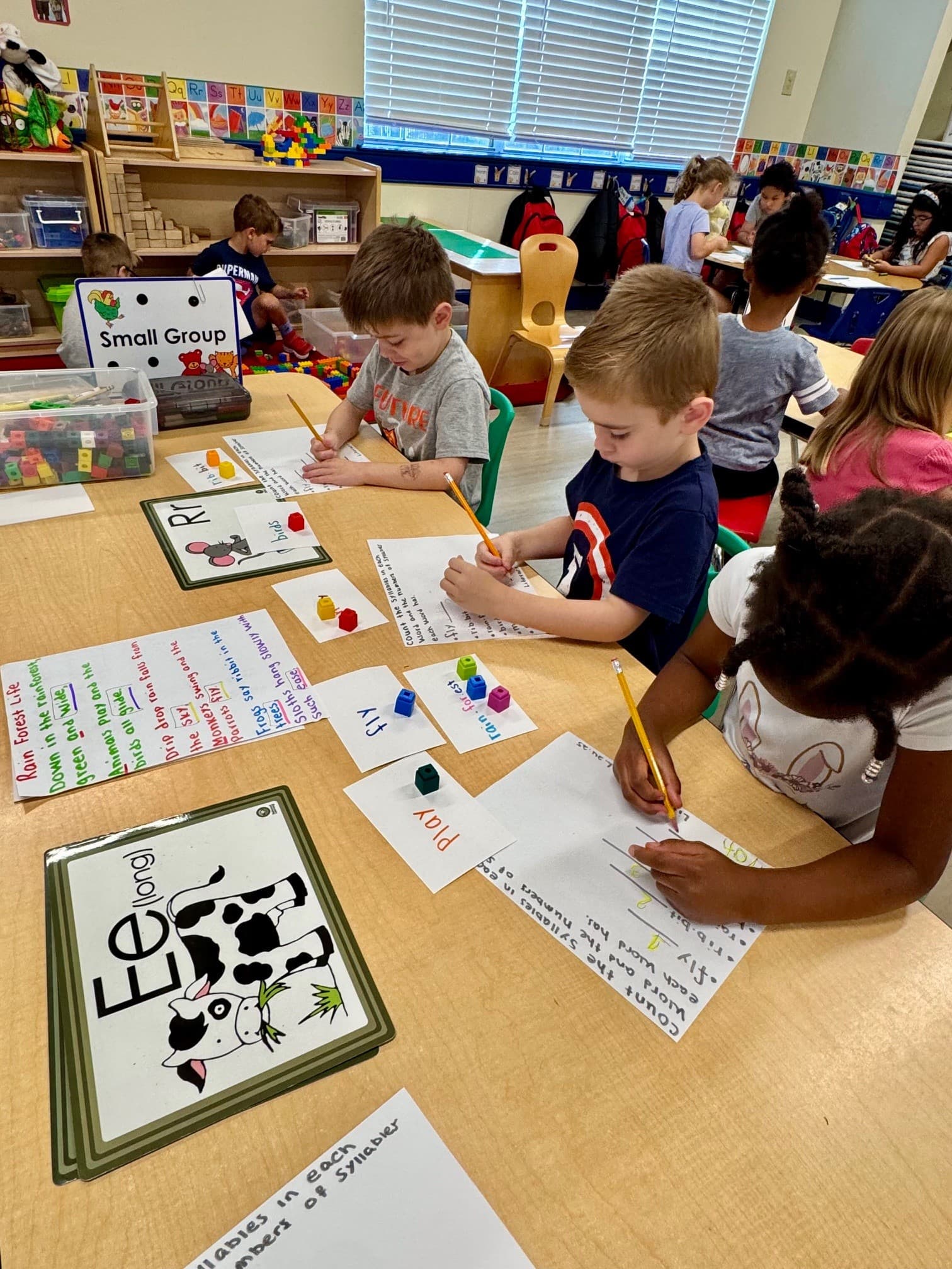Preschool students in a small group practicing letter recognition, writing and counting syllables