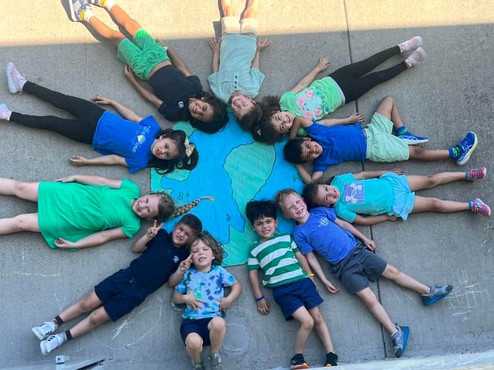 children posing in a circle with a hand drawn picture of the earth