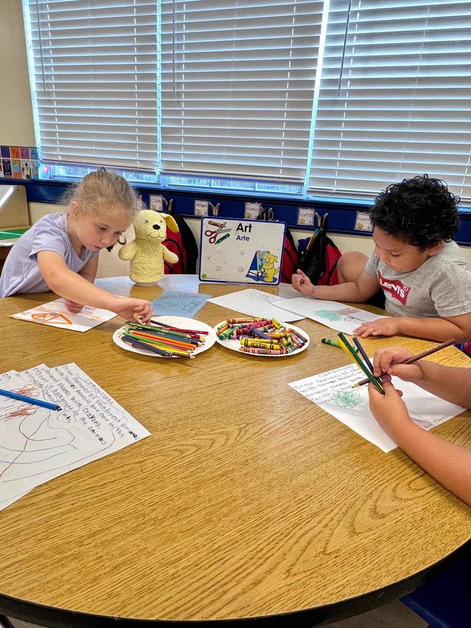 Students utilize crayons and markers mediums to create a picture in the art center
