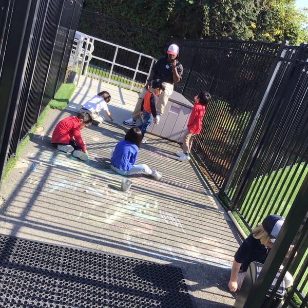 Pre-Kindergarten decorating our walkway with chalk outside by the playground
