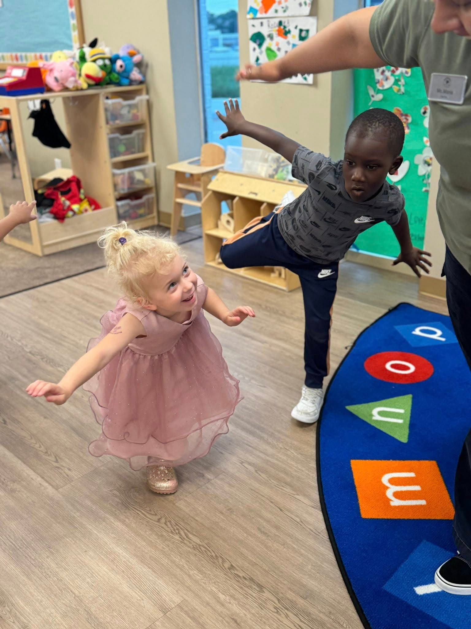 children playing a balancing game with their teacher in the classroom