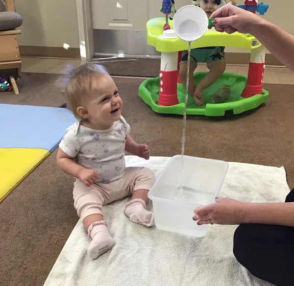 Student watching water being poured representing rain.