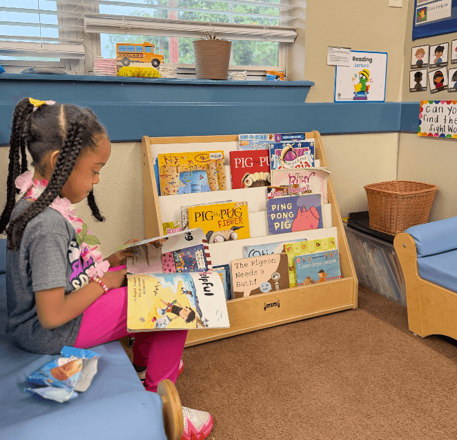 Preschool child participating in Pre-K Roundup, reading in a balanced learning reading center while exploring books and engaging with hands-on classroom materials in a bright, welcoming early childhood environment.