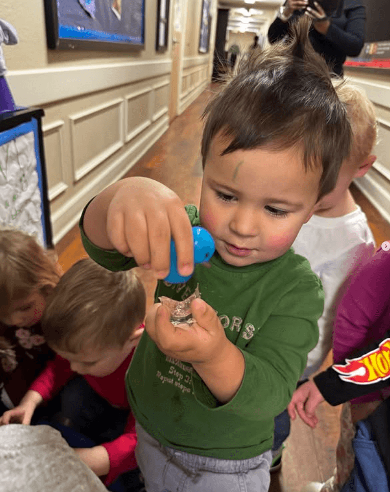 Toddler holding a small blue rubber duck during a classroom activity at Primrose School of Thornton