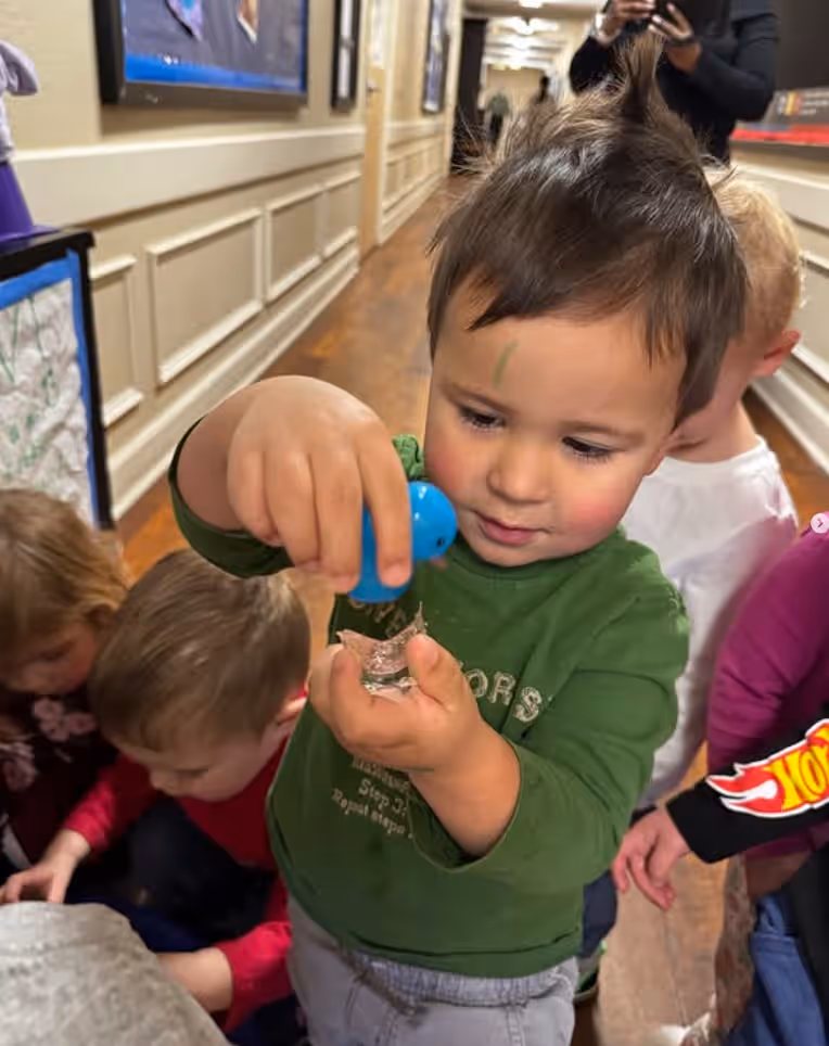 Toddler holding a small blue rubber duck during a classroom activity at Primrose School of Thornton