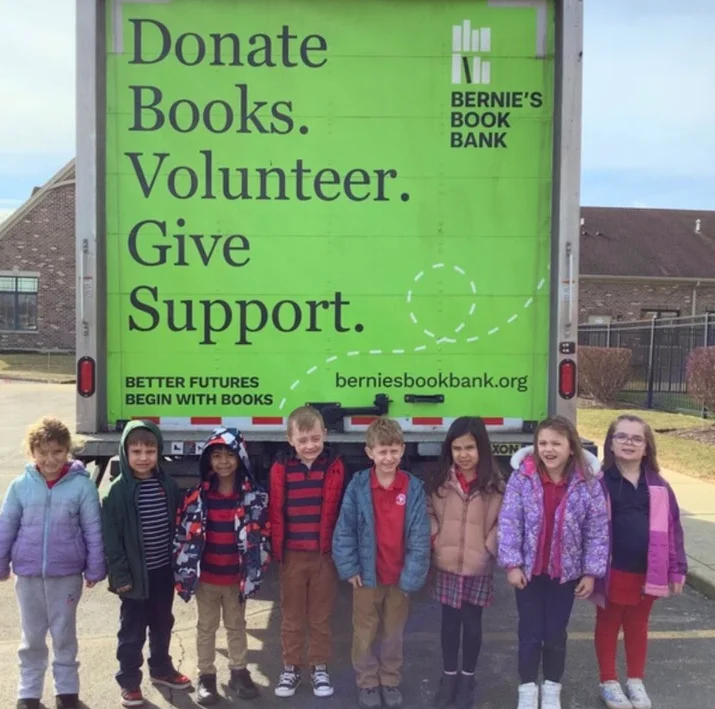 Group of students standing outside beside a book donation truck after a school book drive at Primrose Denver North