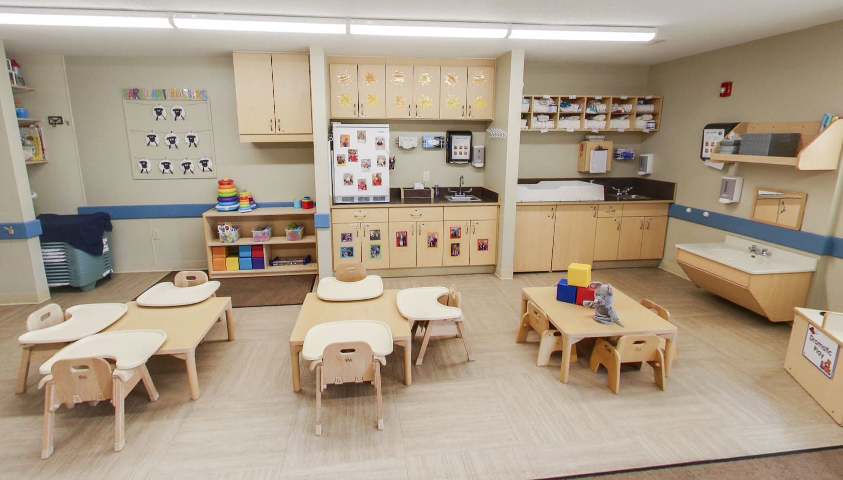 Primrose School of Eagan toddler classroom featuring age-appropriate tables and chairs, a dramatic play area, hands-on learning materials, dedicated diapering station, and child artwork displayed on the walls.