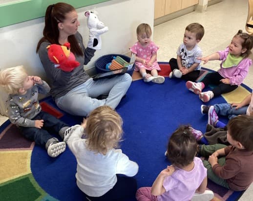 Toddlers sitting in a circle with their teacher during Circle Time at Primrose School of Thornton