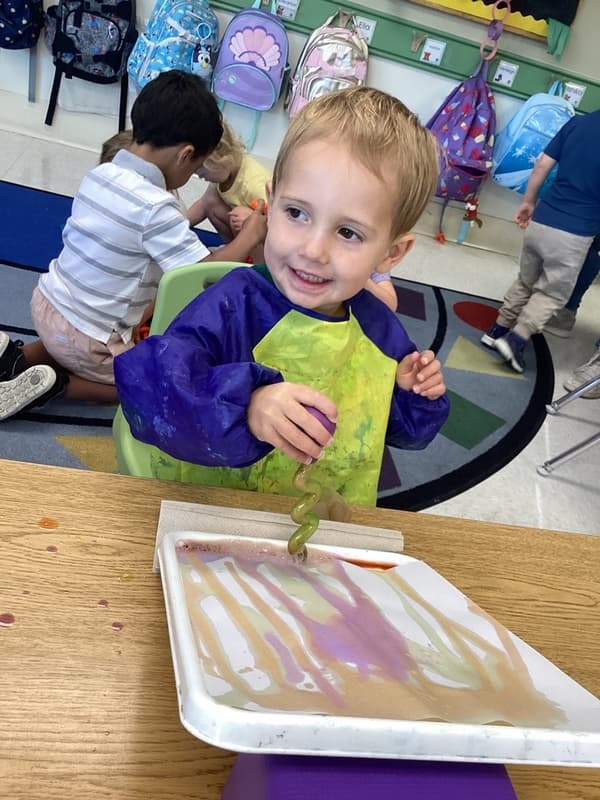 A boy with a dropper and smock on participating in art