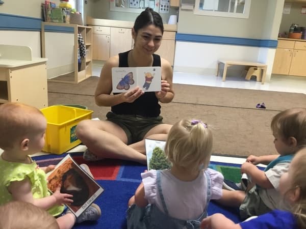 Teacher siting on the floor with the children reading a book