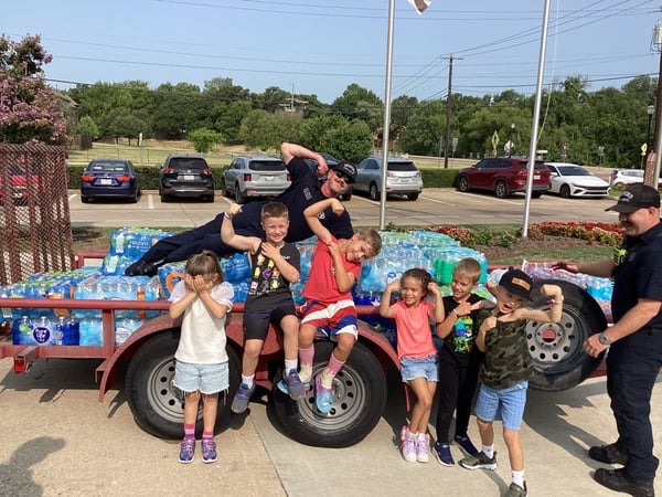 a trailer loaded with water bottles and sports drinks with firefighters and students posing in front