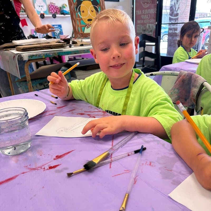Child exploring drawing and painting during a hands-on creative arts activity in the Before and After School program at Primrose School at Highlands Ranch Business Park.