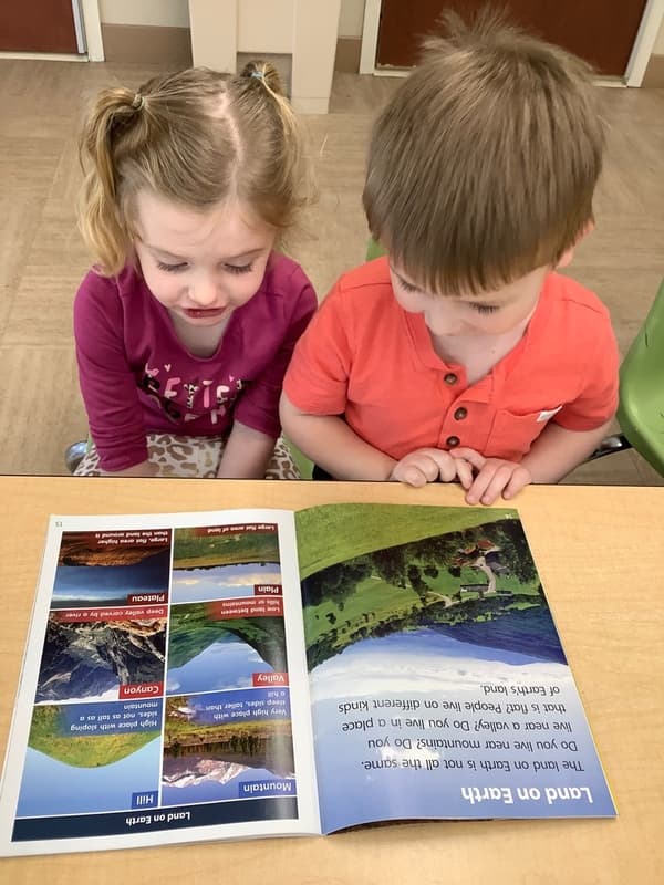 Preschool children reading a nonfiction book about landforms together