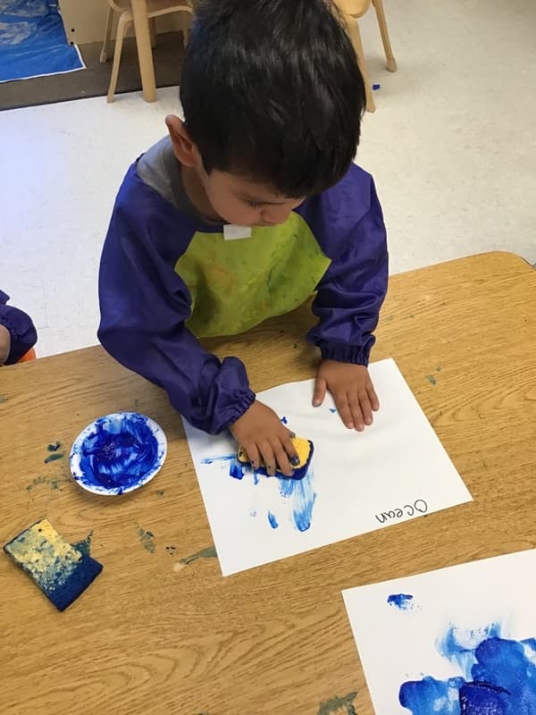 Picture of a boy painting with a sponge and blue paint