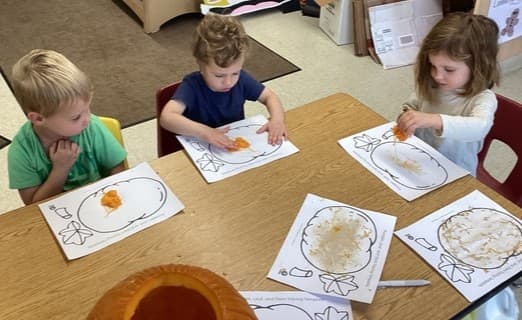 Preschool students exploring pumpkin seeds and pulp at a classroom table at Primrose School of Thornton
