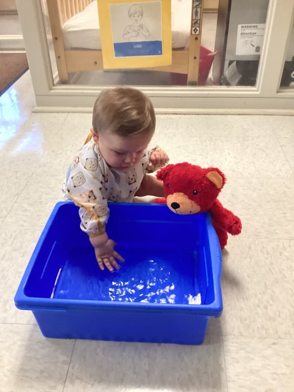baby splashing in water with Benjamin the Bear