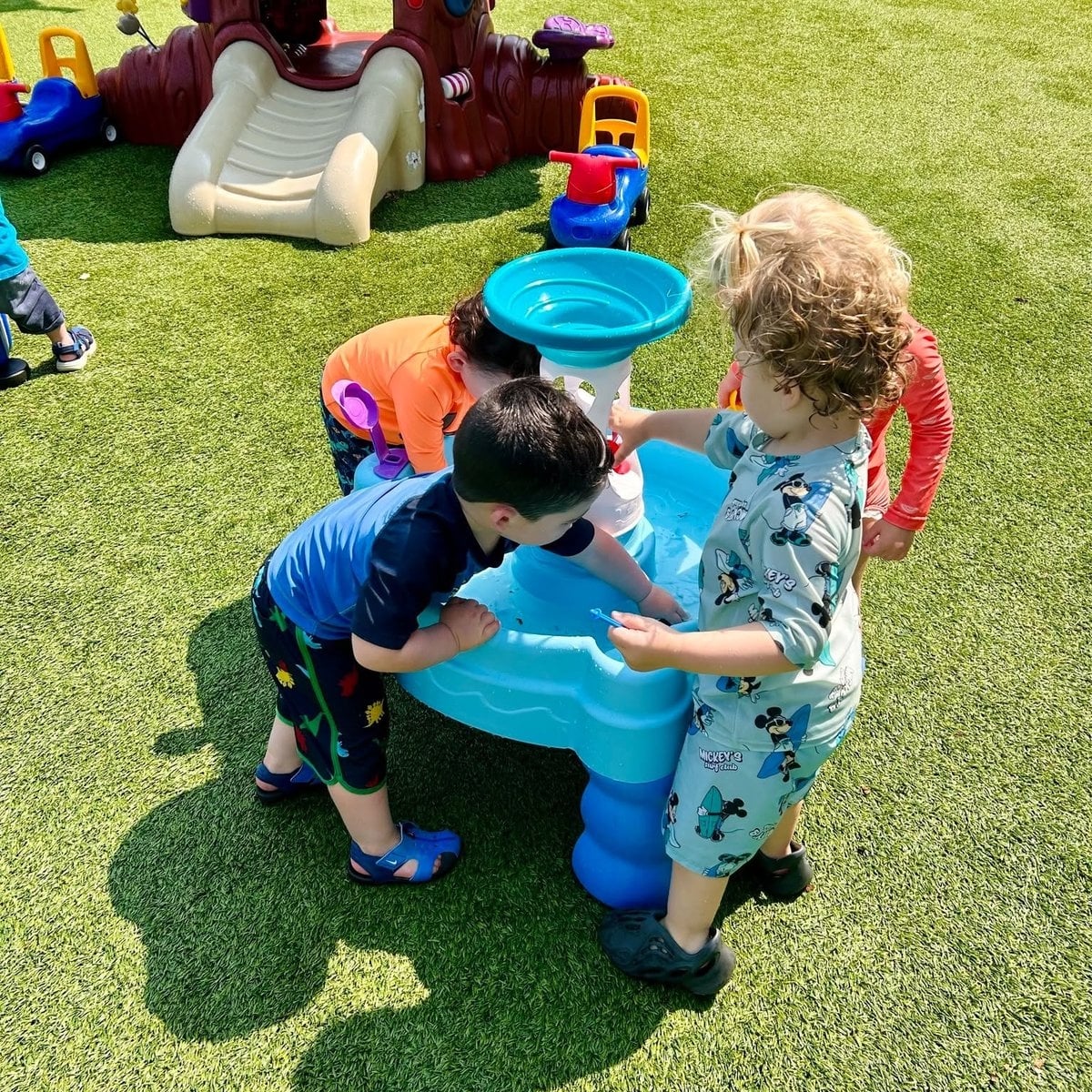 Early preschool children gathered around a butterfly habitat with their teacher at Primrose School of Woburn, MA