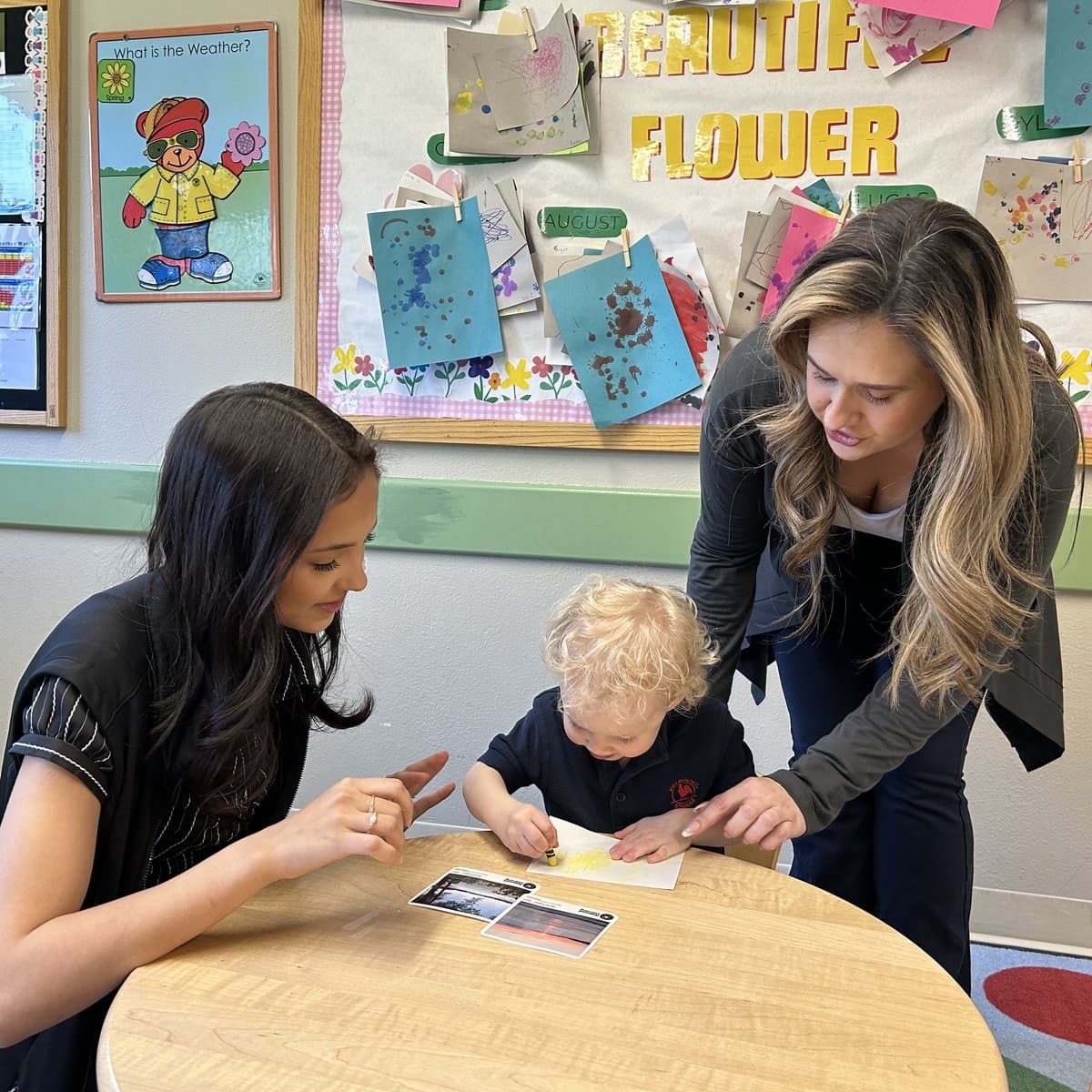 Two teachers guiding an early preschool child through a hands-on activity at Primrose School of Chelmsford in Chelmsford, MA