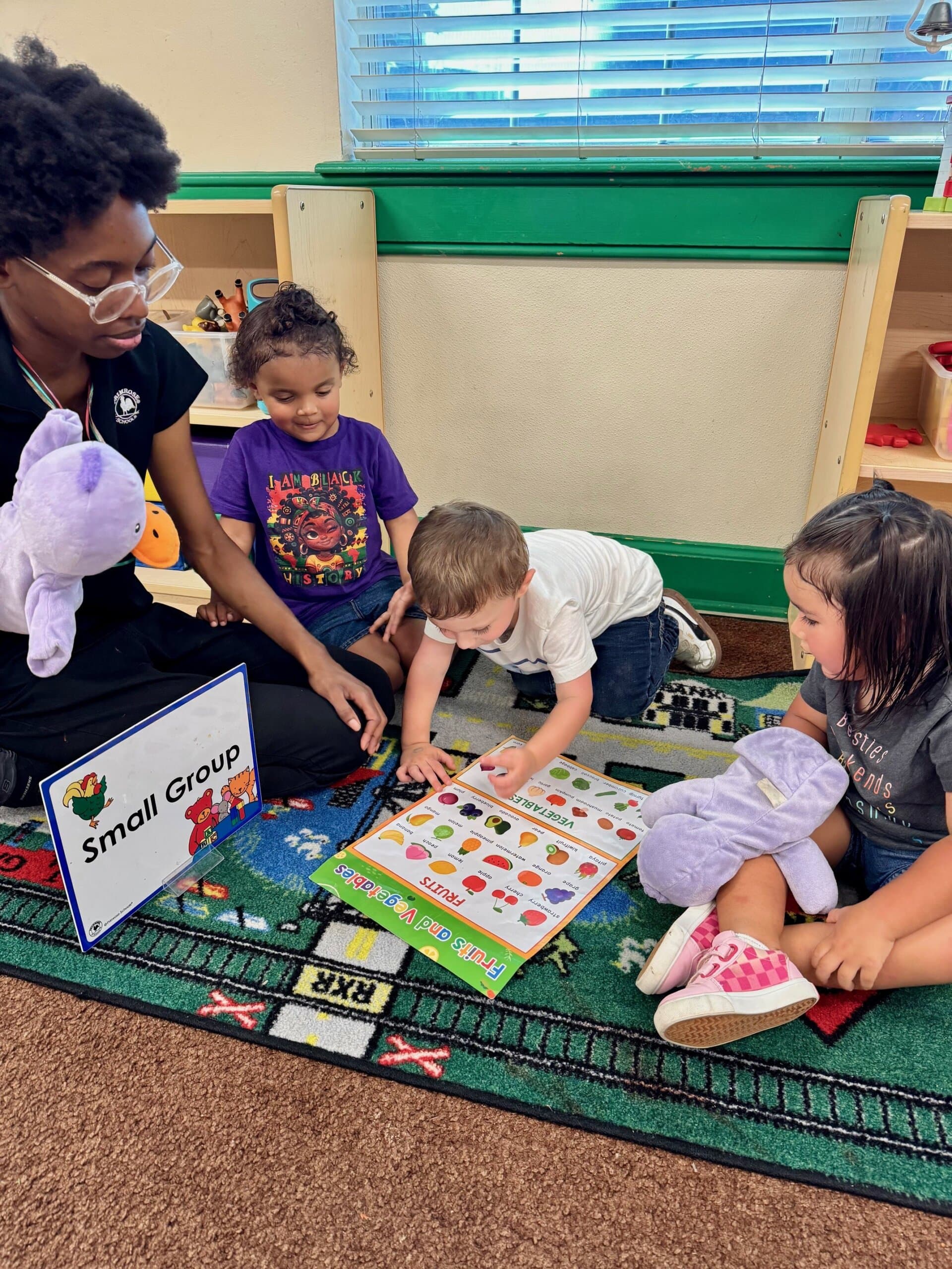 Preschool students participating in a small group activity, identifying different fruits by name and color, promoting early learning and social interaction