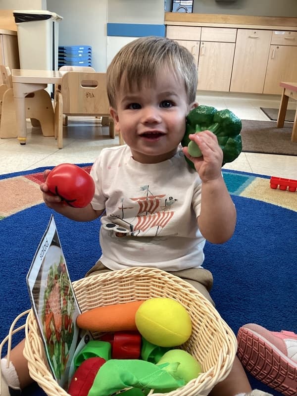 Toddler exploring healthy foods through imaginative play at Primrose School, supporting cognitive development and early childhood education.