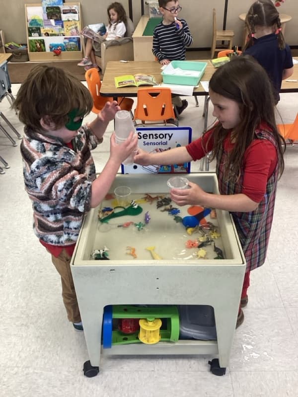 A boy and girl playing in water in the sensory table