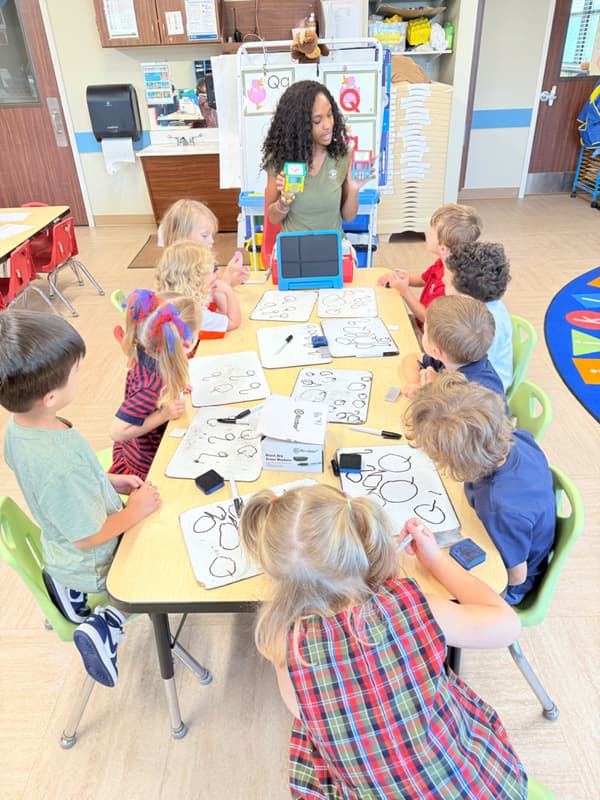 Teacher at small group table implementing a literacy lesson with Pre-K students