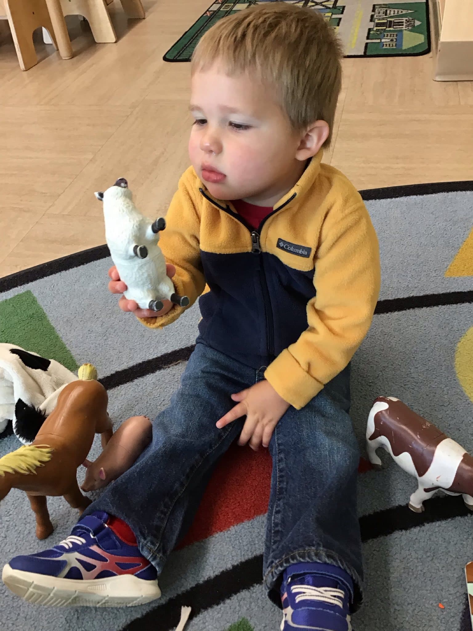 A child playing with animals and practicing the sounds they make.