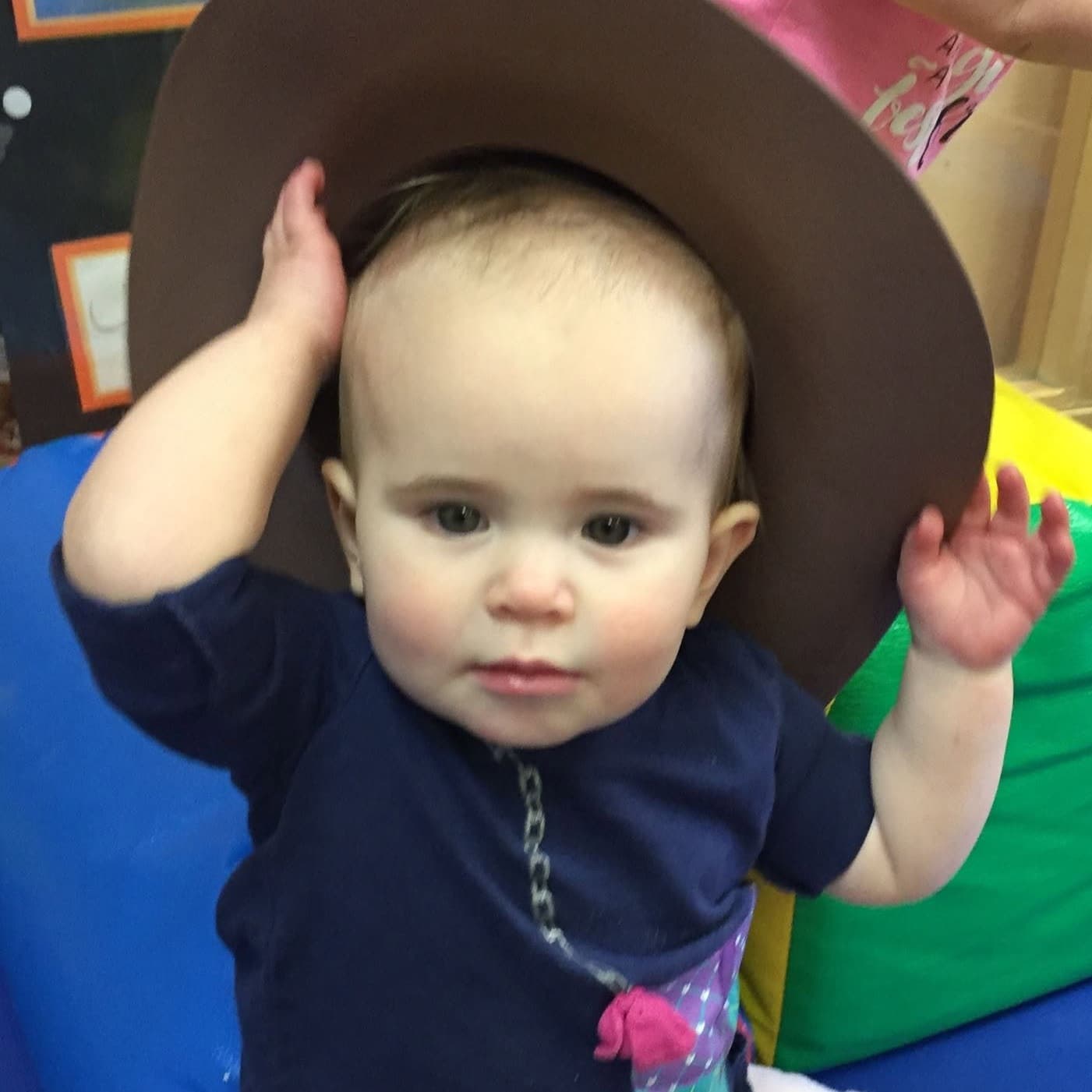 Infant exploring a large hat during a classroom activity at Primrose School at Highlands Ranch Business Park in Highlands Ranch, CO.