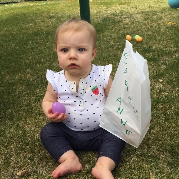 Infant holding a colorful egg during an outdoor activity at Primrose School at Highlands Ranch Business Park in Highlands Ranch, Colorado.