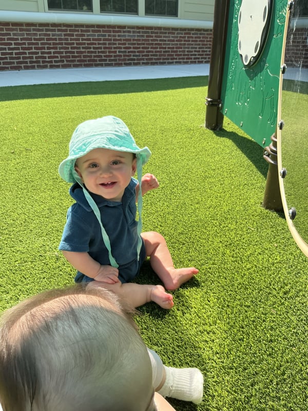 An infant wearing a sunhat enjoying Primrose's playground