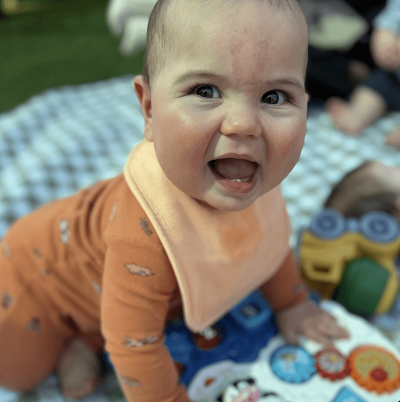 Smiling infant crawling during playtime at Primrose School of Chelmsford infant daycare program in Chelmsford, MA