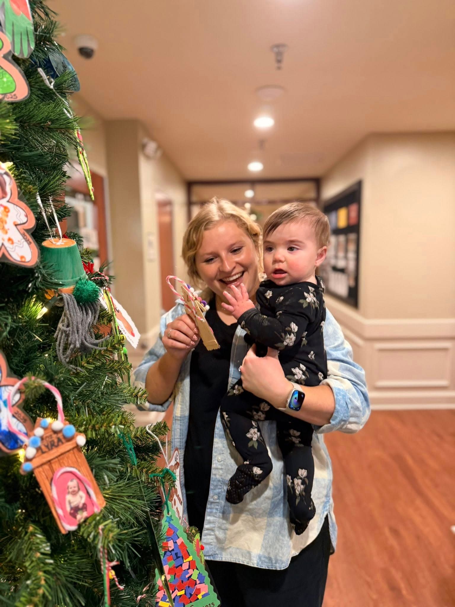 A infant putting an ornament on the tree!