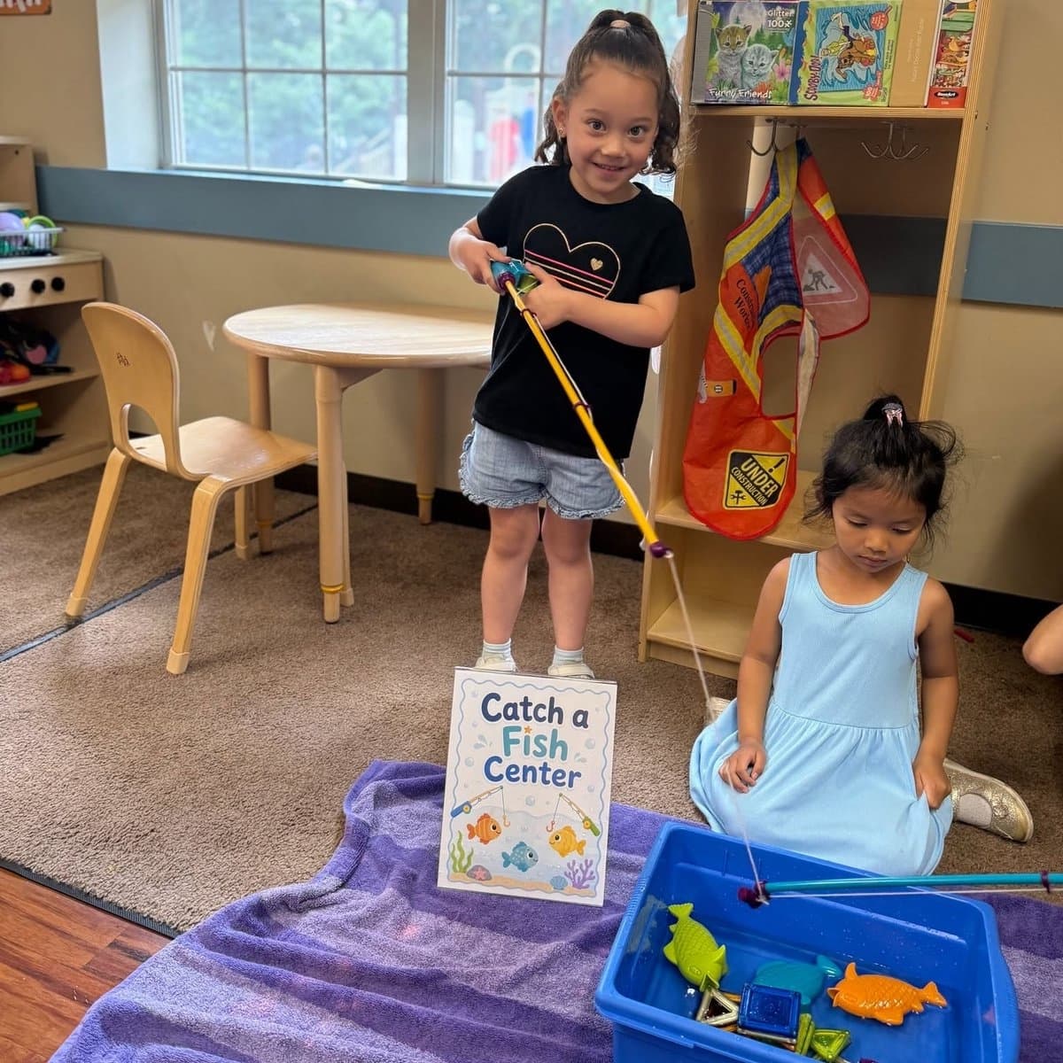 Two kindergarten girls playing at a magnetic fishing center in the classroom at Primrose School of Chelmsford, MA