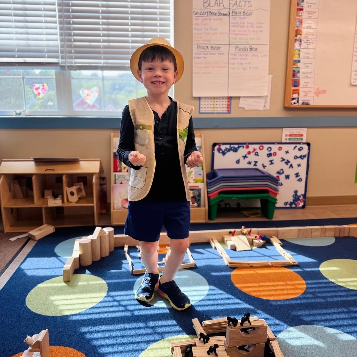 Kindergarten child in explorer costume posing with wooden block structures during creative classroom play at Primrose School of Woburn, MA