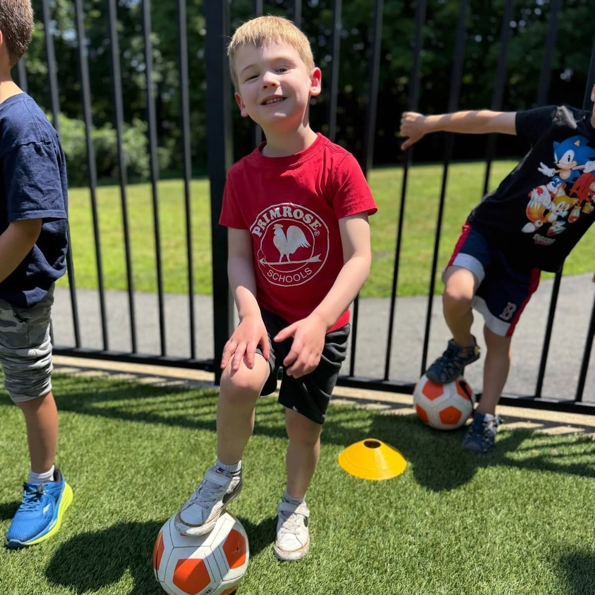 Kindergarten boy lying on a colorful outdoor activity surface during summer play at Primrose School of Chelmsford, MA