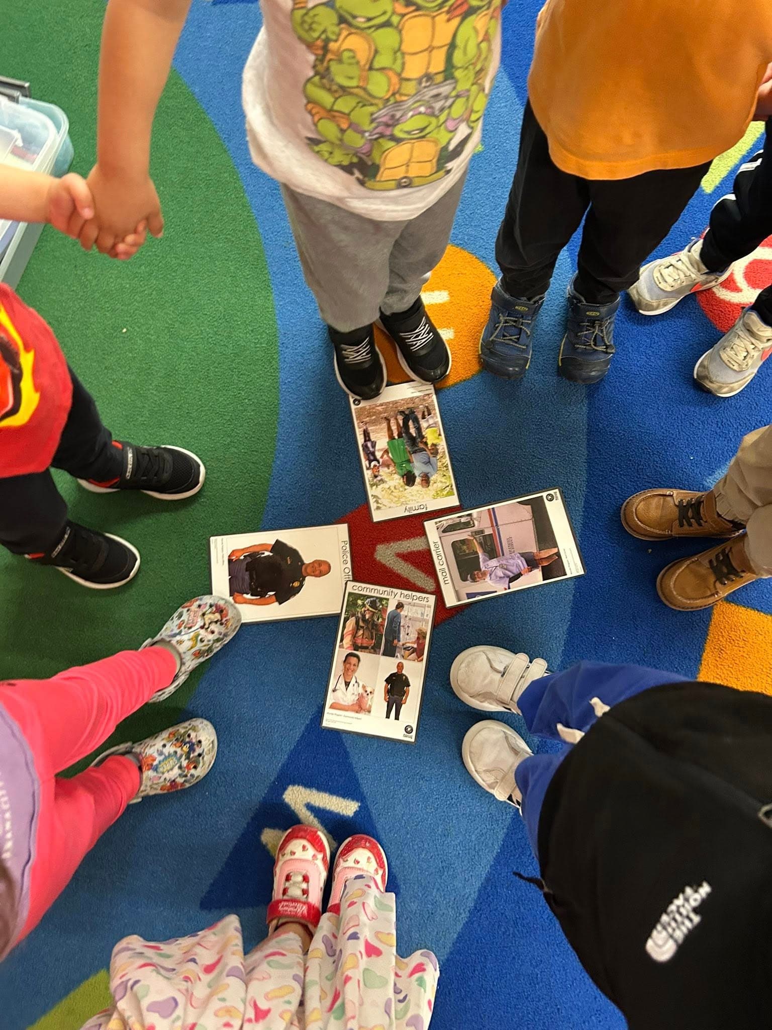 Children standing around cards with fire fighters and doctors on them