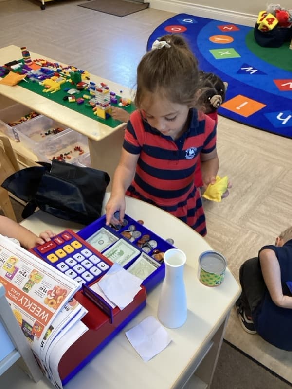 child uses a pretend cash register in the classroom