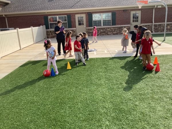 Children kicking a ball around a cone