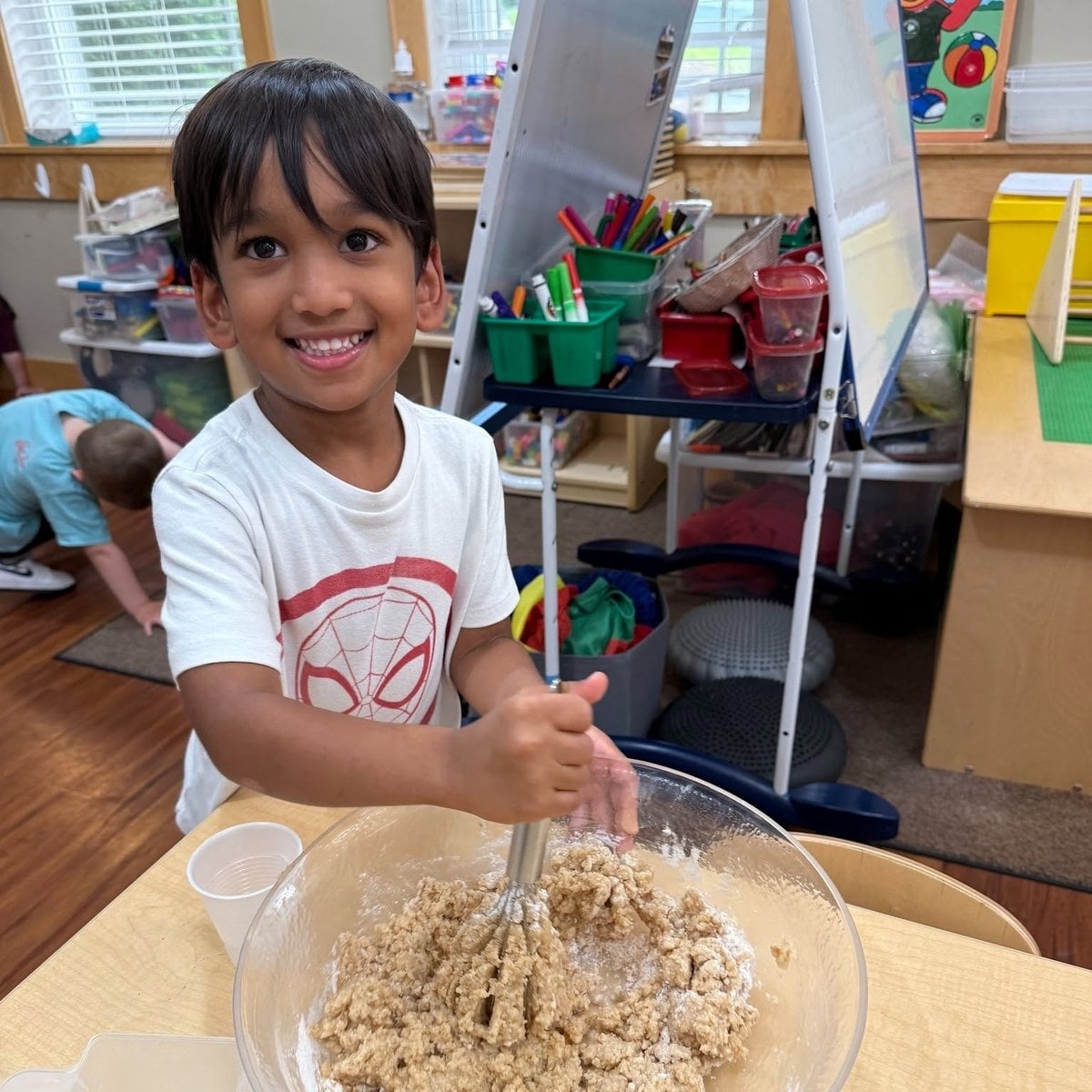 Pre-K boy mixing batter during a cooking activity at Primrose School of Chelmsford pre-kindergarten program in Chelmsford, MA