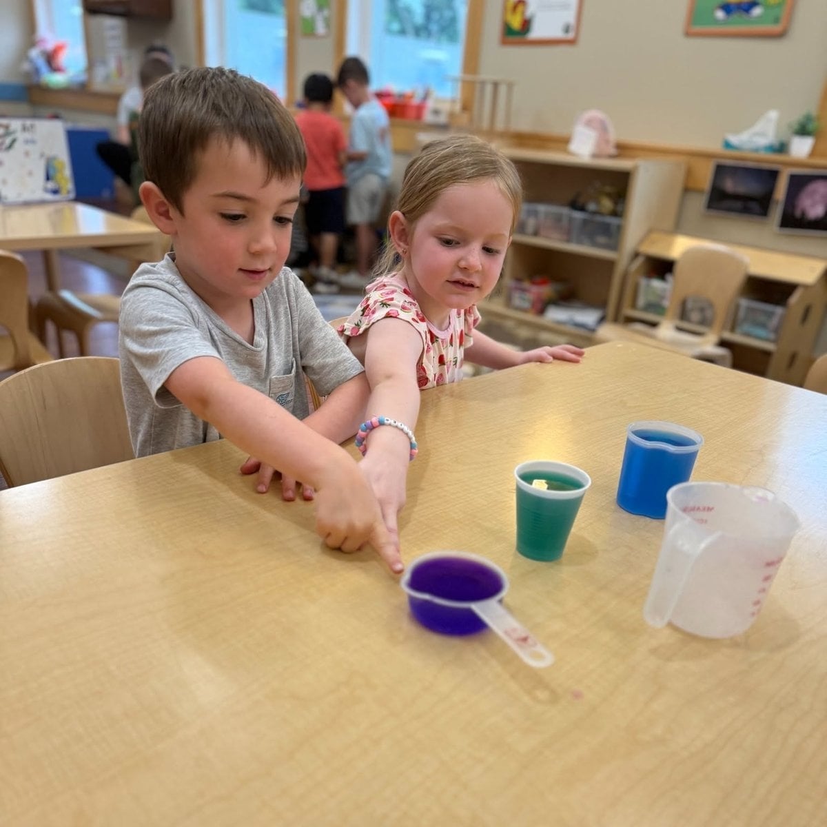 Two Pre-K children exploring color mixing with water and cups during a hands-on science activity at Primrose School of Chelmsford, MA
