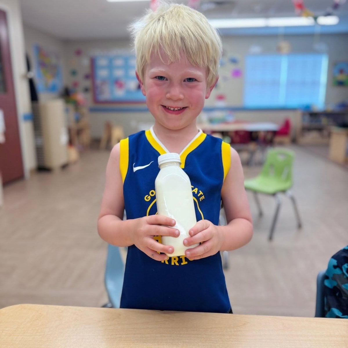 Pre-K child proudly holding a science experiment in the classroom at Primrose School of Woburn, MA