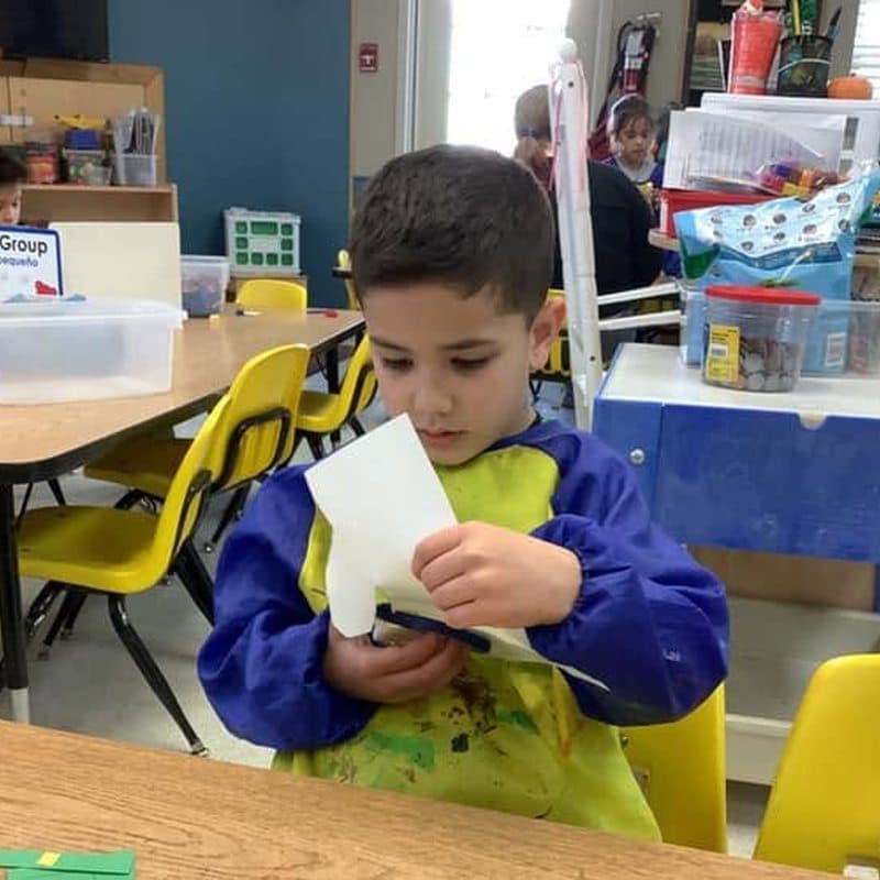 Pre-Kindergarten student exploring a hands-on creative paper activity at Primrose School at Highlands Ranch Business Park in Highlands Ranch, CO.