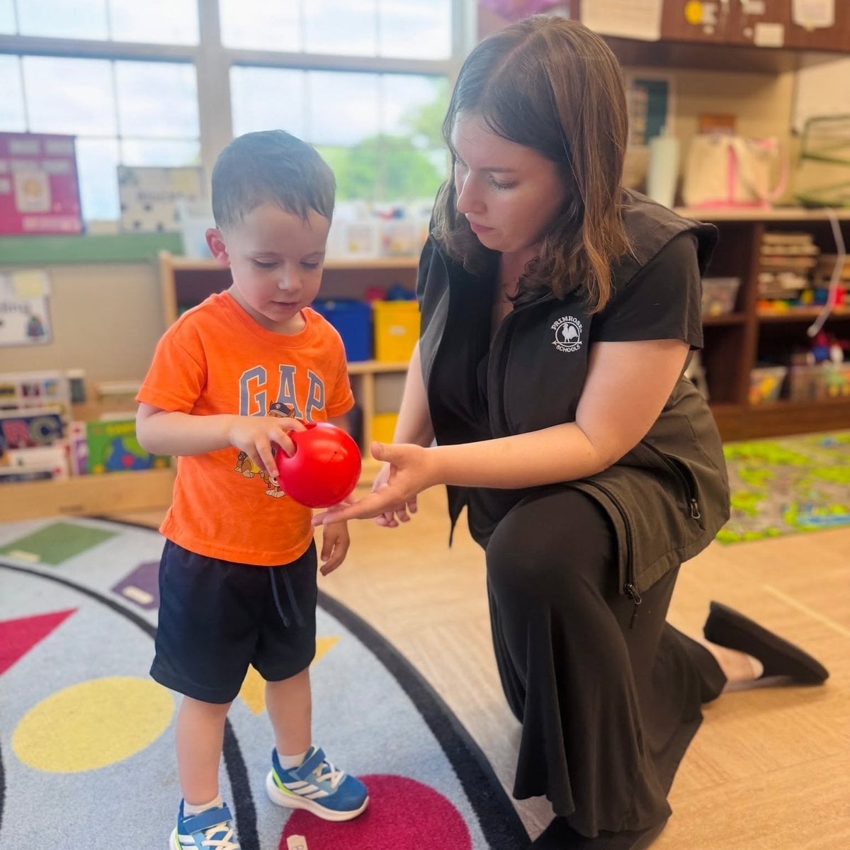 Preschool child and teacher engaged in a hands-on learning activity inside the classroom at Primrose School of Woburn, MA