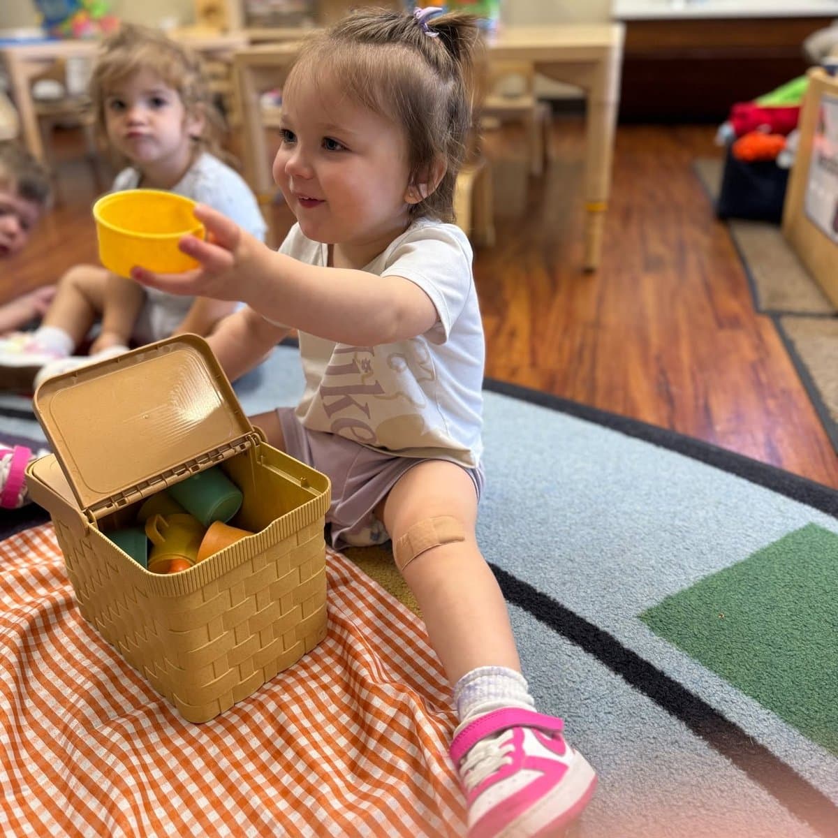 Preschooler playing with a picnic basket during dramatic play in the Preschool Pathways classroom at Primrose School of Chelmsford, MA