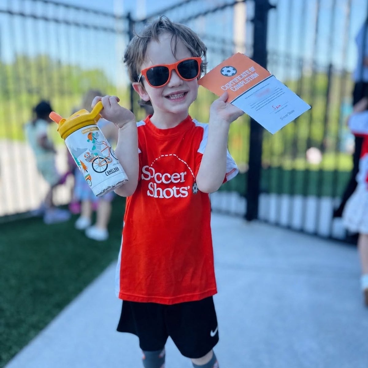Summer Adventure Club child holding a Soccer Shots certificate of completion at Primrose School of Woburn, MA