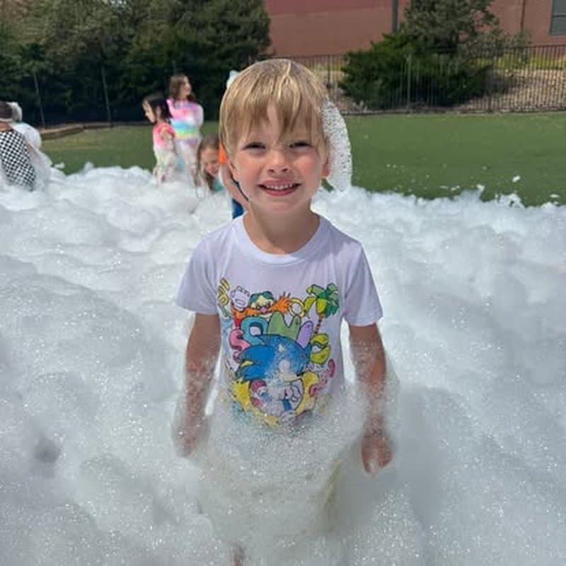 Smiling child enjoying a bubble-filled outdoor summer activity at Primrose School at Highlands Ranch Business Park in Highlands Ranch, CO.