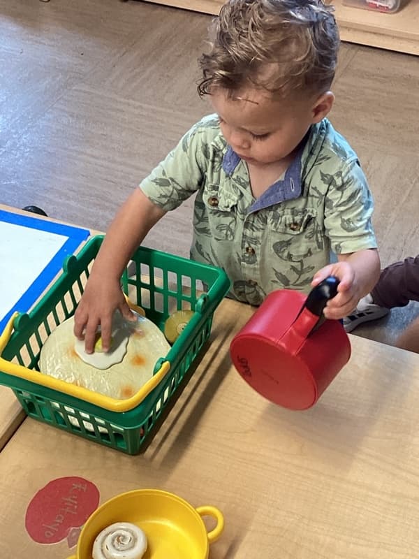 toddler explores dramatic play kitchen