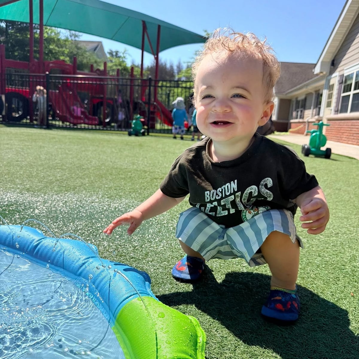 Smiling toddler playing outdoors at the Primrose School of Chelmsford daycare playground in Chelmsford, MA